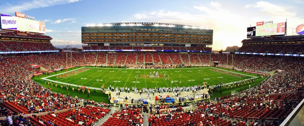 A stunning panoramic shot of Levi's Stadium in Santa Clara during a packed football game at sunset.