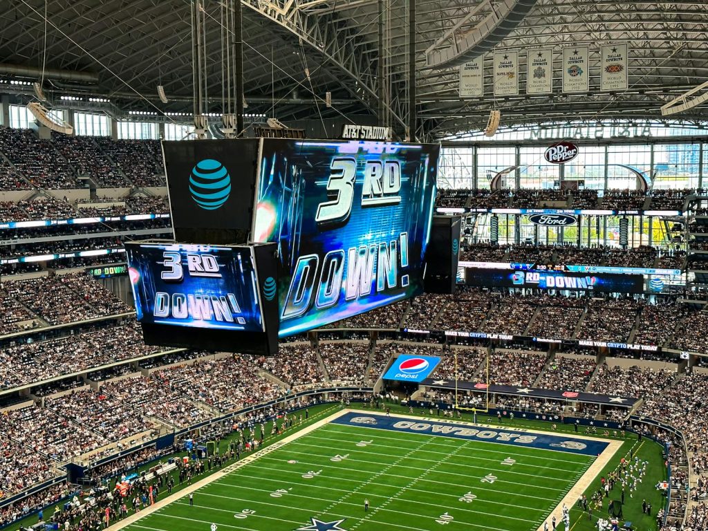 An exciting football game is underway at the AT&T Stadium in Arlington, Texas, with a packed crowd and dynamic atmosphere.